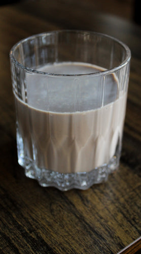 Rich and creamy Irish cream liqueur served in a faceted glass on a dark wood tabletop, perfect for slow sipping.