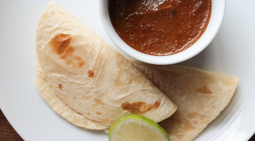 A plated view of Smoky Chocolate Mole served with slow-roasted pork carnitas.