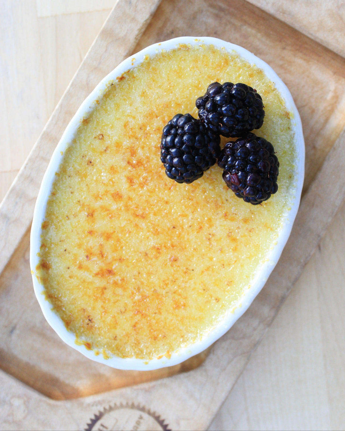 Creme bréleé with blackberries on a wooden board