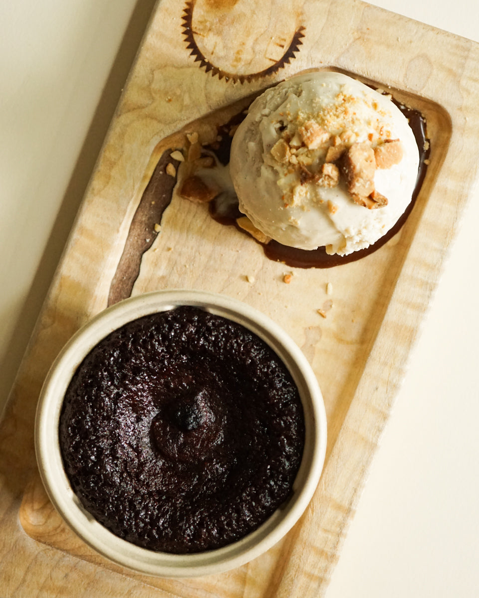 Vegan Gooey Brownie Molten Cake with vegan ice cream and toppings on a wooden board
